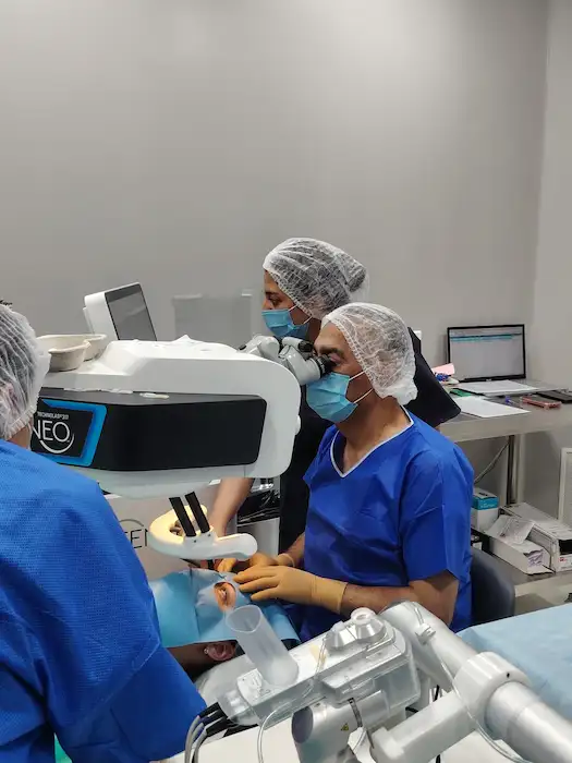 clinique-de-la-vue-chirurgie-refractive-laser-teneo-bausch-lomb-ophtalmologue-bron-lyon Chirurgien en salle de chirurgie ophtalmologique à Lyon utilisant un microscope et un écran de guidage numérique pour une intervention oculaire précise